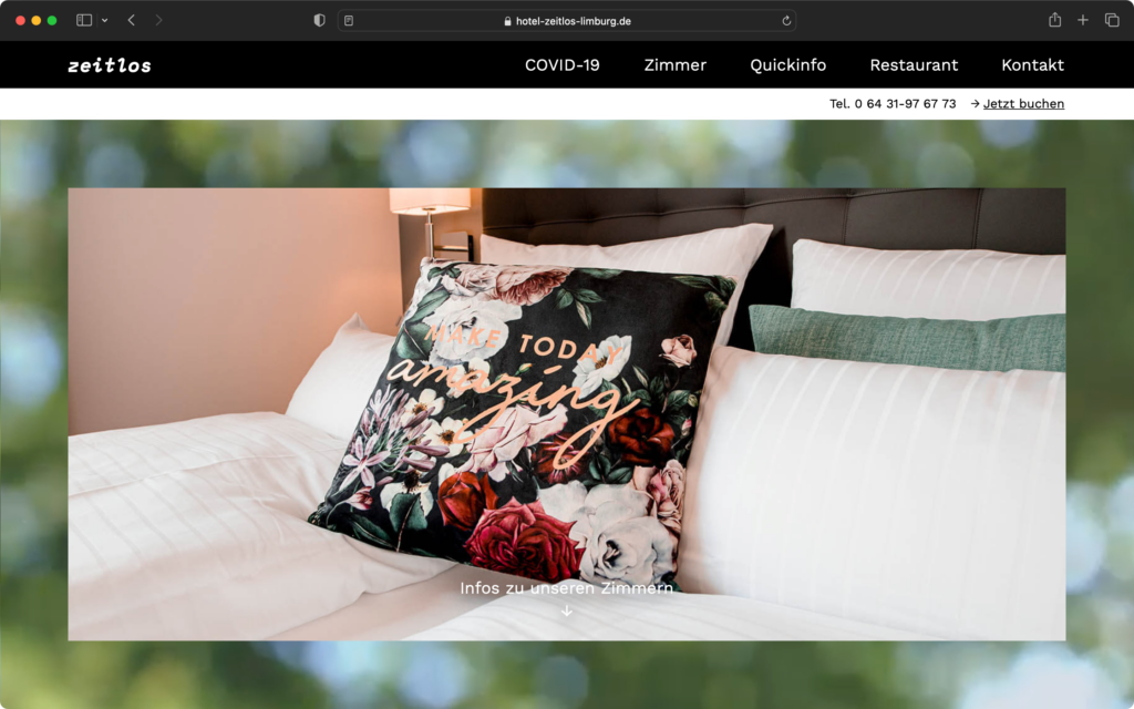 Bett mit weißen Kissen und einem dekorativen Kissen mit Blumenmuster und dem Schriftzug Make Today Amazing.