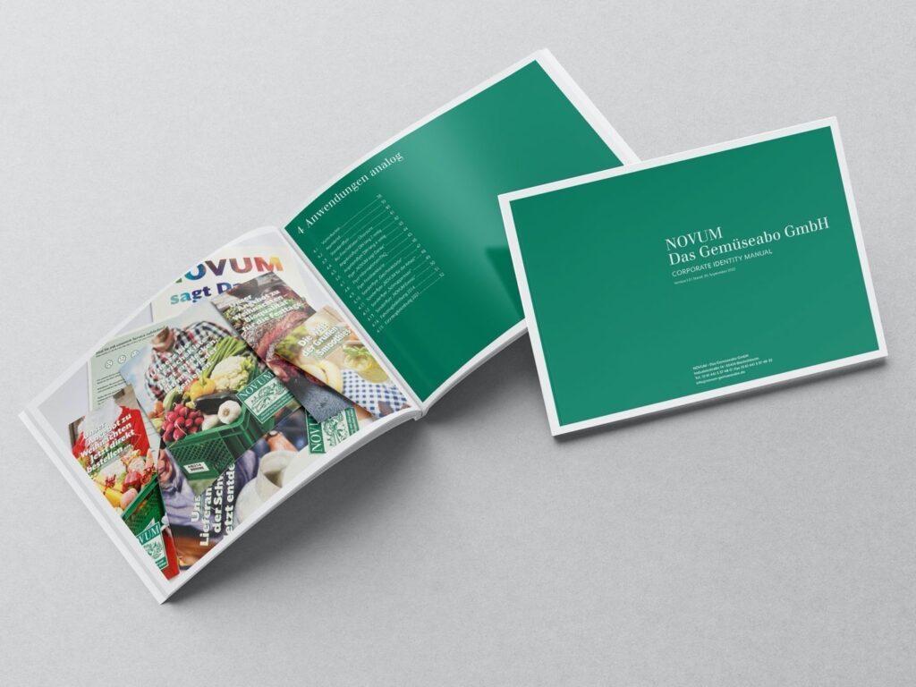 Zwei aufgeklappte Broschüren liegen auf grauem Untergrund, eine zeigt das Inhaltsverzeichnis, die andere den Titel des Corporate Identity Manuals der Gemüseabo GmbH.