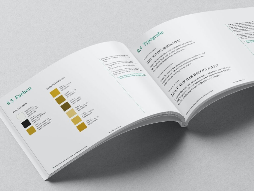 Offenes Buch mit Farbpalette und Typografie-Anleitung in deutscher Sprache auf grauem Untergrund.