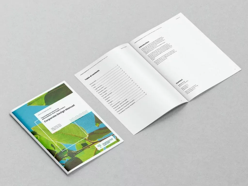 Zwei geöffnete Broschüren liegen auf grauem Untergrund, eine zeigt das Inhaltsverzeichnis, die andere das Cover mit Blättern und blauem Himmel.