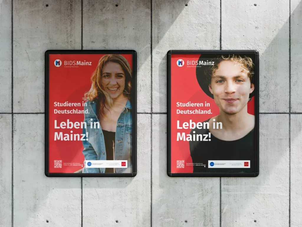 Zwei Plakate an einer Betonwand mit der Aufschrift Studieren in Deutschland Leben in Mainz und Porträts von einer Frau und einem Mann.